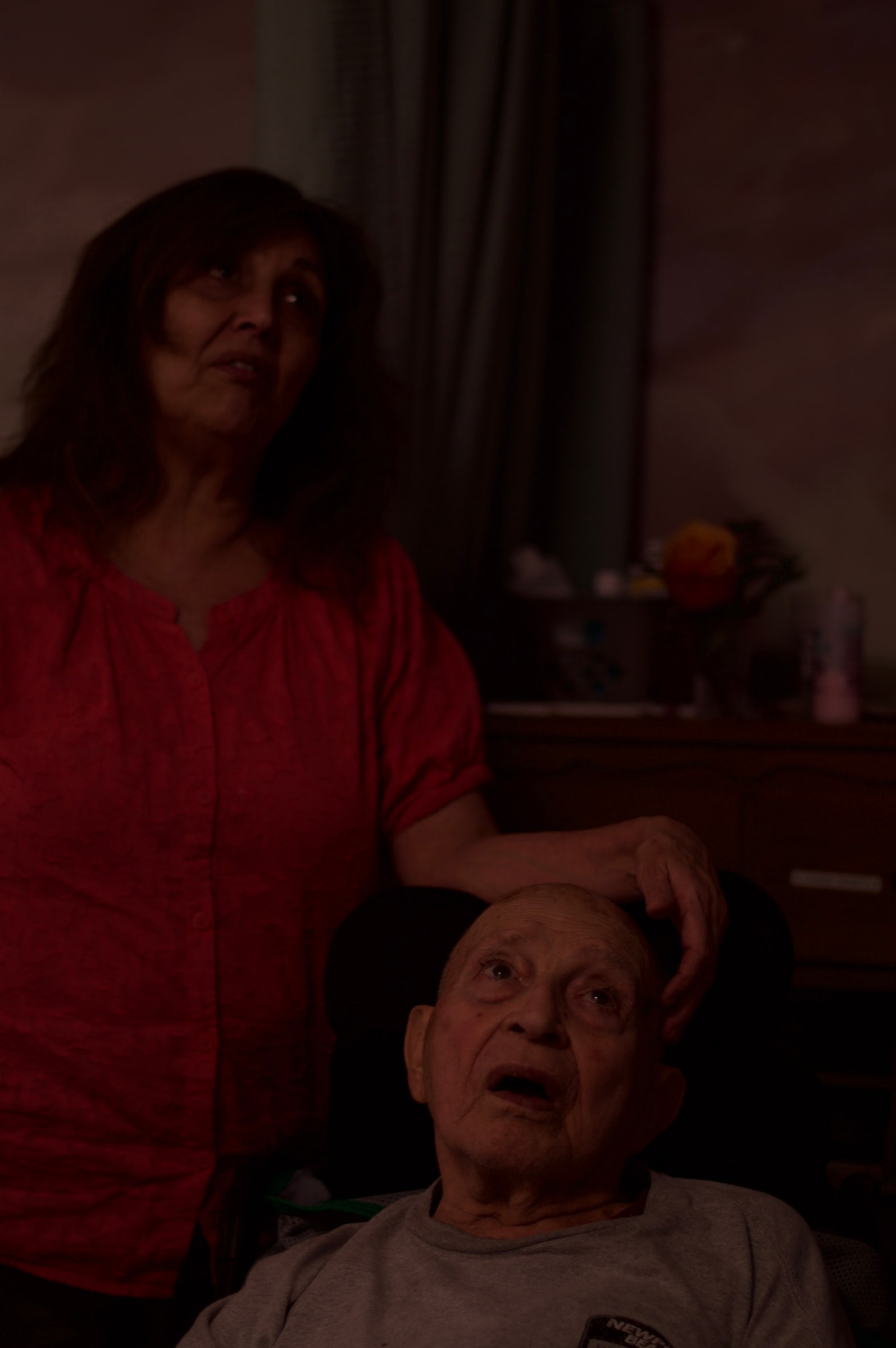 Two people together in a softly lit room.