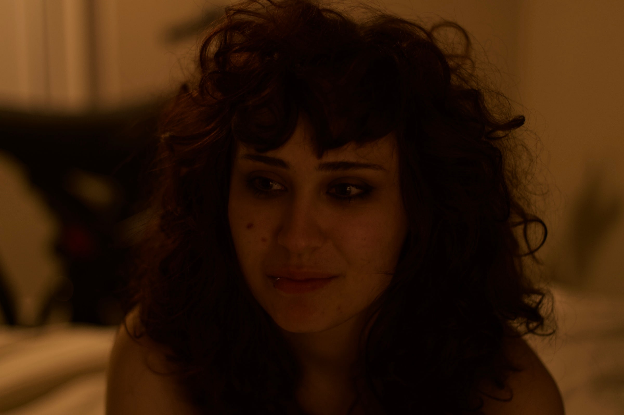 A curly-haired person in soft amber indoor light.